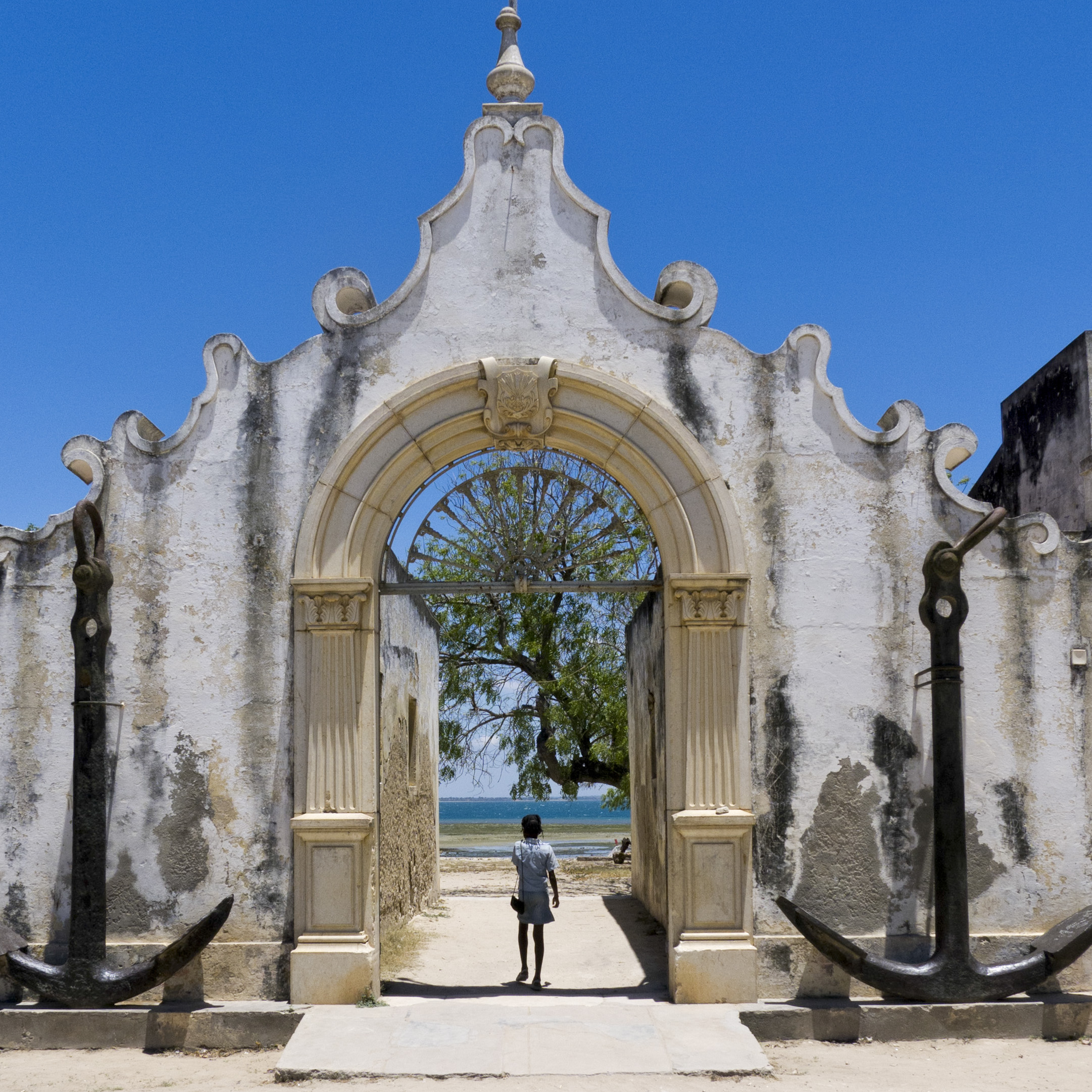 The historic waterfront gateway at Ilha de Moçambique, with a person walking towards the sea